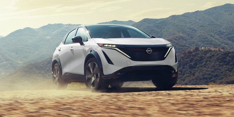 Nissan Ariya driving through the desert kicking up sand during the process